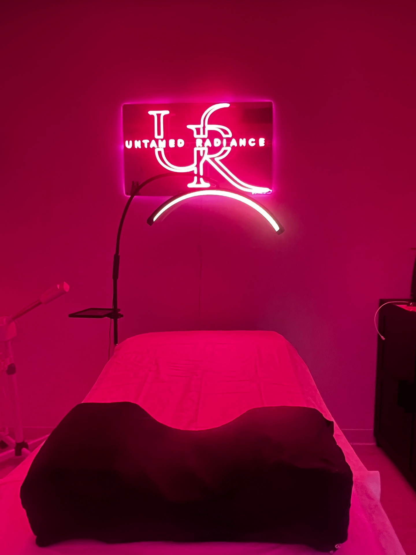 Untamed Radiance treatment room with pink neon UR sign above the facial bed